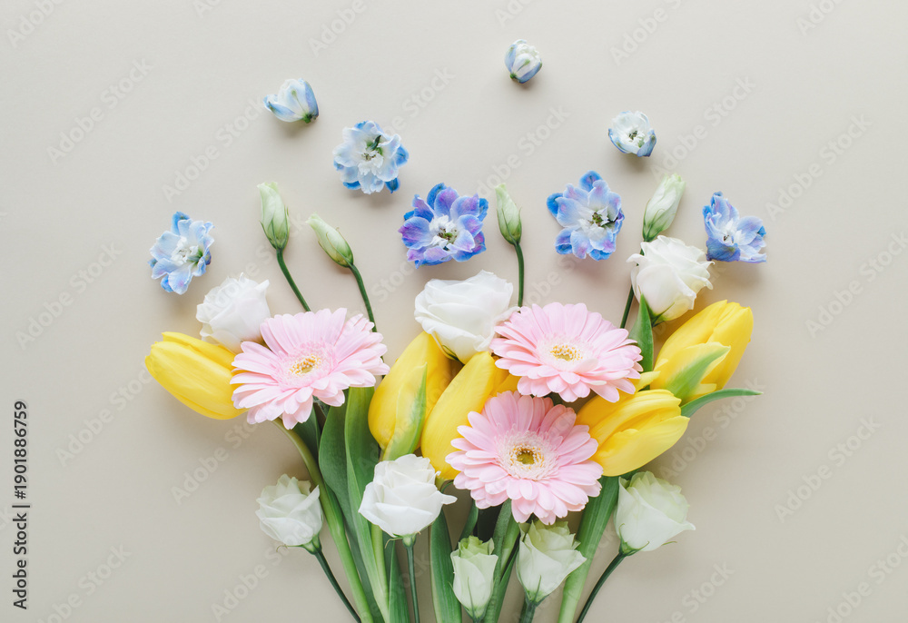 Fototapeta premium Bouquet of beautiful spring flowers on pastel white table top view. Greeting card for International Women Day or Mother day. Flat lay.