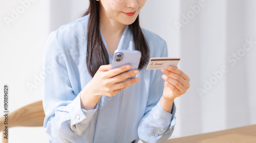 Bild auf Leinwand クレジットカードを見ながらスマホを操作する女性