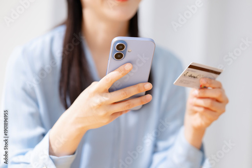 Bild auf Leinwand クレジットカードを見ながらスマホを操作する女性