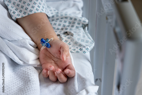 Patient hand with iv drip receiving medical treatment