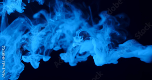 Ethereal blue smoke swirls elegantly against a dark background, creating a mysterious and atmospheric scene.