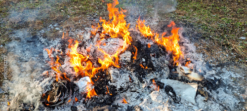 Φωτογραφία A large outdoor fire burning piles of paper and household waste into ash and smo