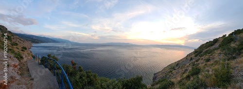 Stunning coastal mountain landscape at sunset Breathtaking panoramic view of mountains and the sea during sunset. Dramatic sky with warm colors reflects on the water Concept of travel, nature, adventu