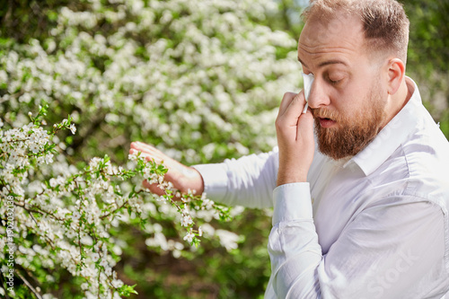 Foto Man allergic suffering from seasonal allergy at spring in blossoming garden at springtime