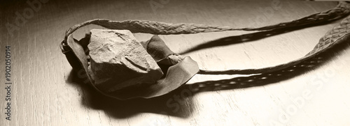 Billede på lærred Sling with stone on wooden background