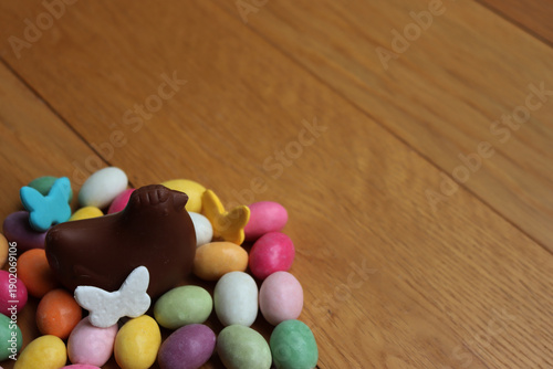 Fotografi Chocolate shaped hen with colorful  sugar and chocolate Easter eggs on wooden table with copy space