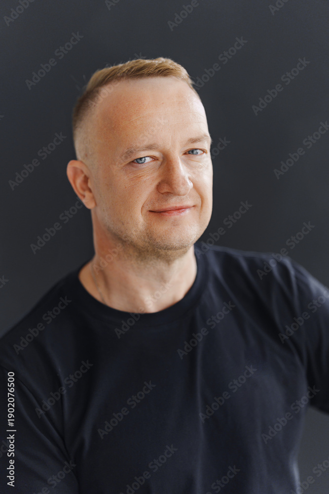 Fototapeta premium Portrait of a man with short hair smiling against a dark background