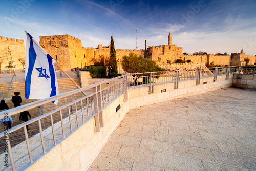 Slika na platnu View of the walls surrounding Old City of Jerusalem during sunset with Israeli flag
