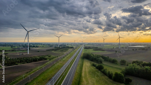 Aerial view of wind turbines and highway in rural Belgium countryside at sunset - renewable energy transition concept