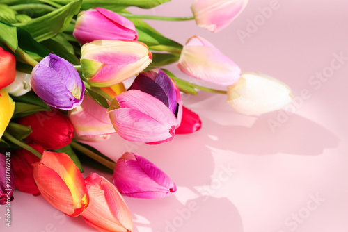 Foto Artificial tulips in various colors are gathered together on light pink surface