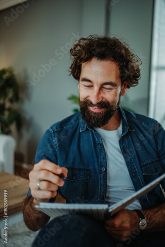 Foto Man with beard writing ideas in notebook at home