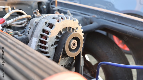 Close up of car engine alternator with spinning serpentine drive belt