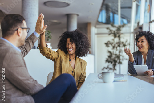 Fényképezés Friends Celebrate Success With A High Five In A Modern Office Meeting Room