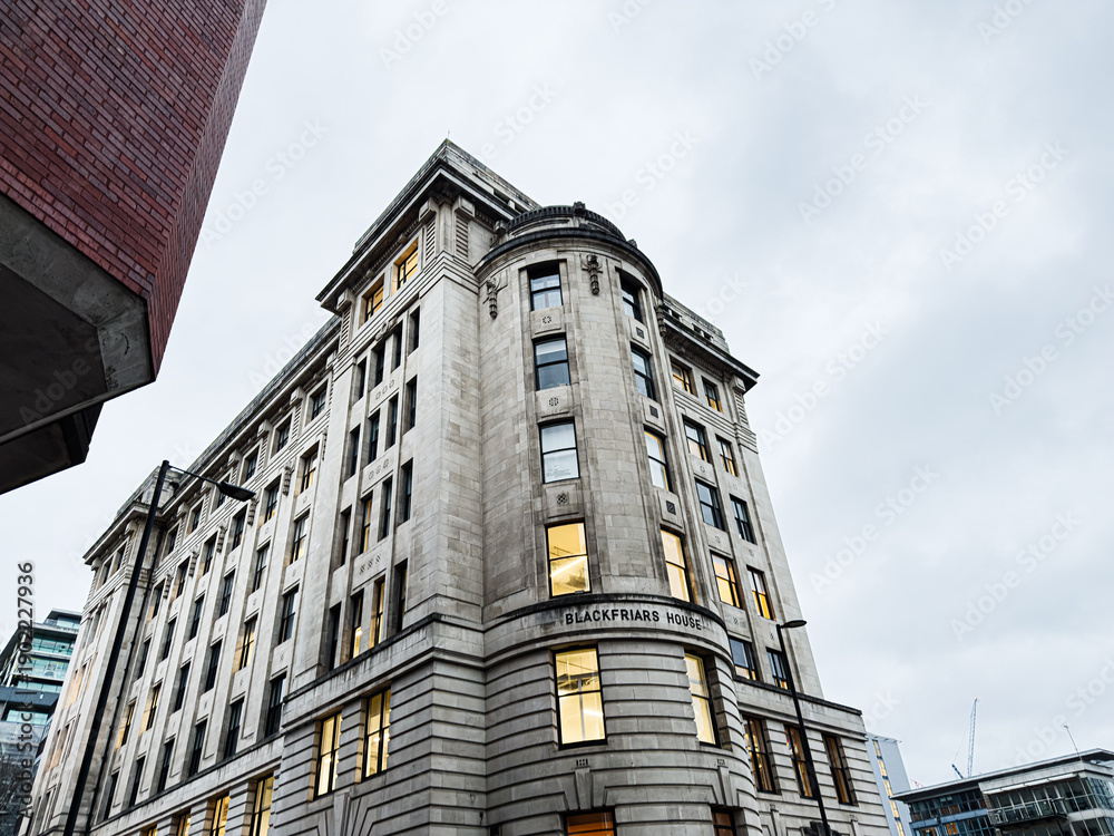 Fototapeta premium Historic Manchester building Blackfriars House rises among surrounding streets under a cloudy sky