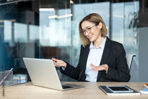 Obraz na plátne Young businesswoman with eyeglasses actively participating in an online video ca