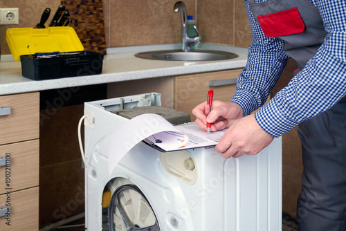 Fotografie A professional repairman washing machine writing an invoice on home kitchen