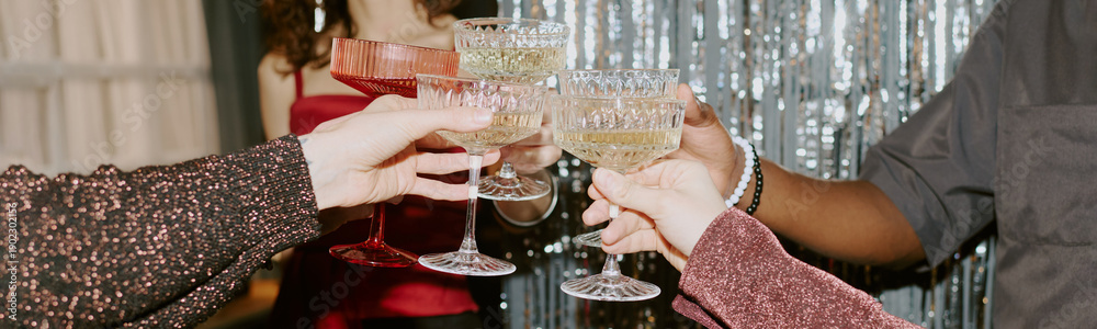 Fototapeta premium Group of young adult women and men of diverse ethnicities clinking champagne glasses during celebration, hands and torsos visible, festive background with shimmering decorations