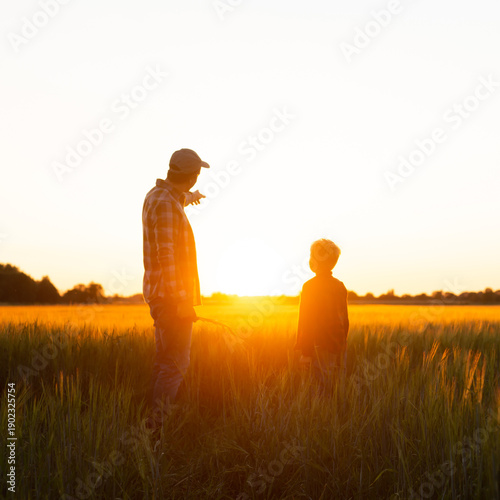 Foto Farmer and his son in front of a sunset agricultural landscape