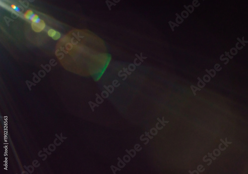 Dark atmospheric frame with dramatic green lens flare streaks and floating light circles creating mysterious cinematic abstract background
