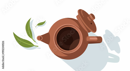 Overhead view of a brown clay teapot with a lid slightly ajar and green tea leaves