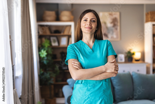 Photo of a happy nurse making a house visit and looking at the camera smiling. Portrait of young adult female healthcare professional.