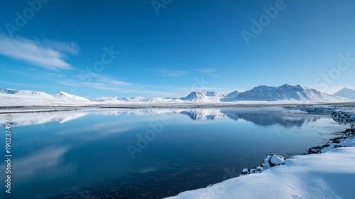 Wallpaper Mural A serene winter landscape featuring a calm lake reflecting snow-covered mountains under a clear blue sky. The scene captures the tranquility of nature in winter. Torontodigital.ca