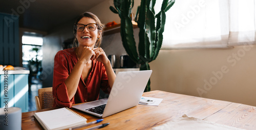 Woman smiling at laptop in bright kitchen
