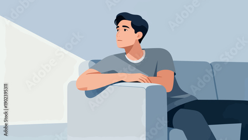 A man is sitting on a couch looking out the window. He is sad or contemplative