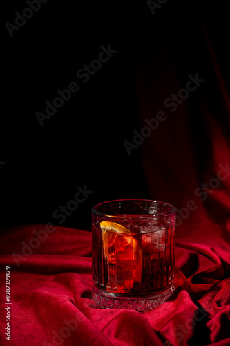 Foto A moody, close-up photo of a vibrant red Negroni cocktail with an orange slice g