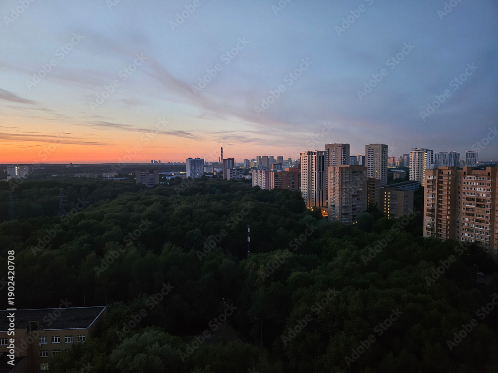 Fototapeta premium City skyline with a beautiful sunset in the background. The sky is filled with clouds and the sun is setting