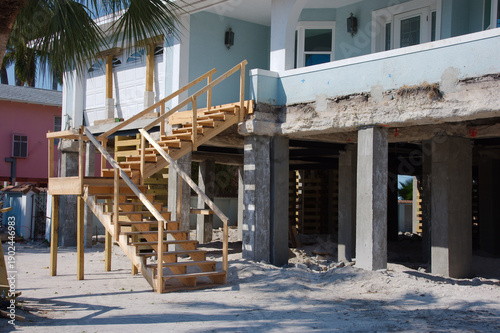 Fotografi Two-Story Beach House Under Construction On concrete Raised Stilts for flood prevention By The Sea Under Clear Sky