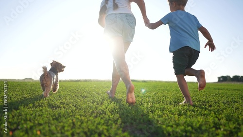 Young boy and girl running in a field. Children running barefoot in a dog park. Family of children running in the park. A young boy and girl are sprinting across lifestyle a field.