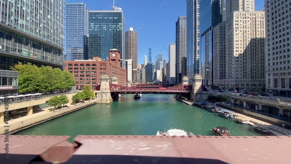 Naklejka premium Chicago establishing shots showing urban architecture and a vivid green chicago river with a classic drawbridge. Boats navigating the clear water