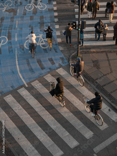 Photography Pedestrians and bicycles gather crossing the street during the golden hour