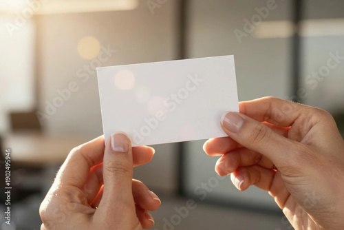 Holding a blank business card in a bright office setting during the day