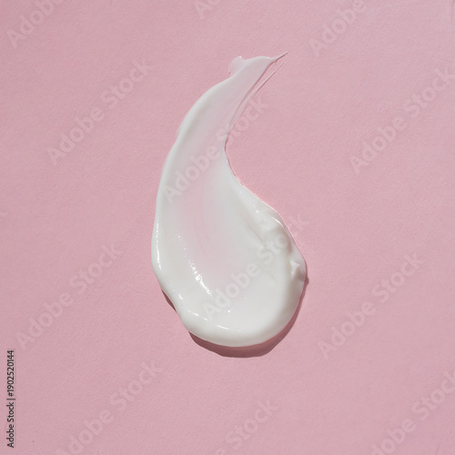 Cosmetic white cream balm texture smudge isolated on pink background.