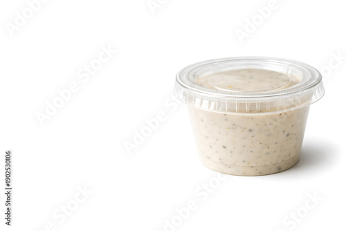 Creamy ranch dressing in plastic container isolated on white background.