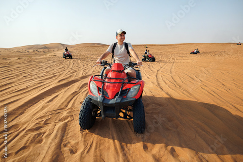Tableau sur toile A man driving a red quad bike on sandy desert dunes