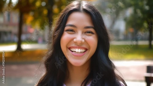 Smiling young woman with long black hair in a park