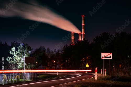 Night Road with Light Trails and Industrial Power Plant Smokestacks