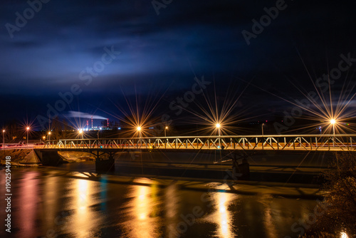 Illuminated Bridge Over River at Night with Light Reflections