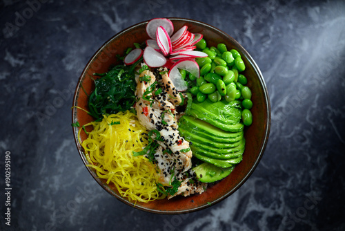Fresh chicken poke bowl featuring sliced avocado edamame seaweed radish and vibrant vegetables