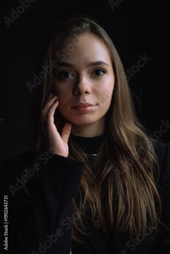 Intimate Low Key Portrait of Young Woman Touching Face with Soft Natural Window Light and Deep Shadows Creating Emotional Cinematic Mood