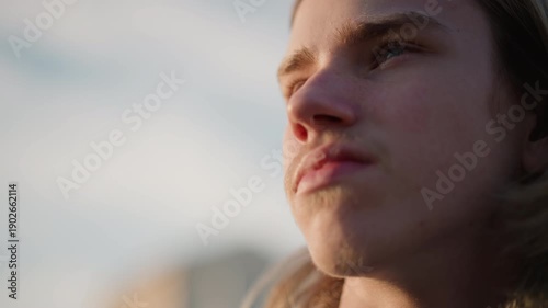 Musician observes sunrise. Peaceful performer watches daylight emerge as breezes softly blow. Tranquil instrumentalist gazes upward during early morning sun with gentle wind surrounding him