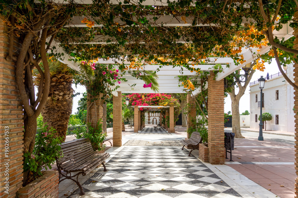 Obraz premium Charming Mediterranean Pergola with Bougainvillea Flowers and Checkerboard Path in Maro Village near Nerja Andalusia Spain