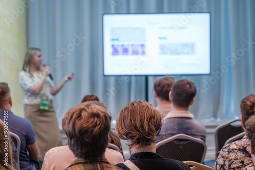 Wallpaper Mural Engaged audience listens to presenter at conference with large screen display and blurred attendees creating dynamic learning atmosphere. Torontodigital.ca