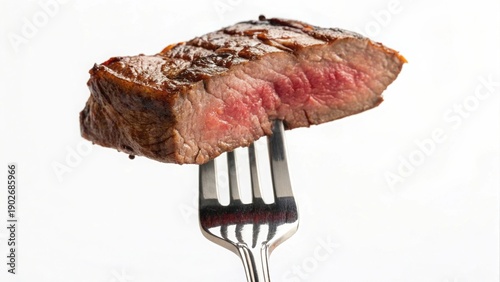 medium-rare steak with a tender pink center and caramelized brown crust hangs from a shiny metallic fork against