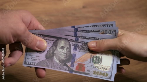 Close up slow motion of two hands pulling and tugging on hundred dollar bills, neither willing to let go.