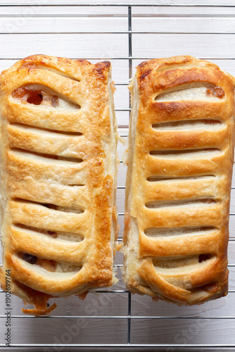 Homemade apple strudels with lattice pastry cooling on a stainless steel wire cooling rack background backdrop.