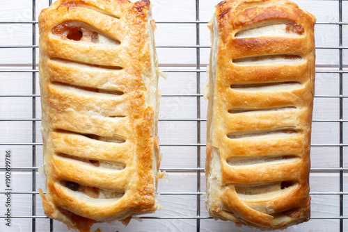 Homemade apple strudels with lattice pastry cooling on a stainless steel wire cooling rack background backdrop.